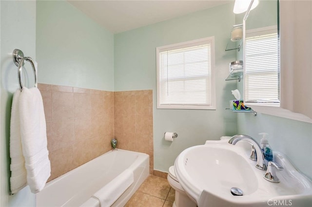 bathroom featuring baseboards, toilet, tile patterned flooring, a washtub, and a sink