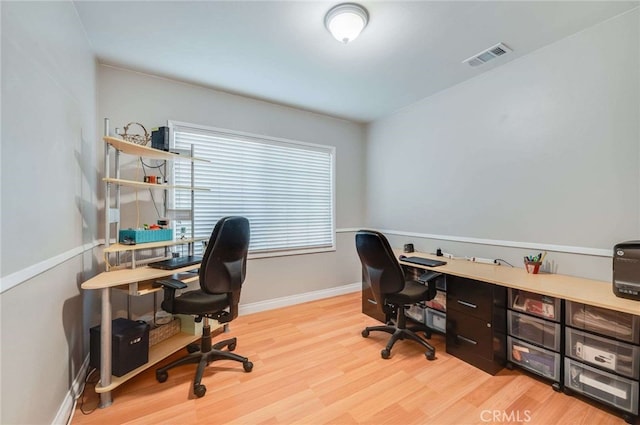 office space with light wood-type flooring, visible vents, and baseboards