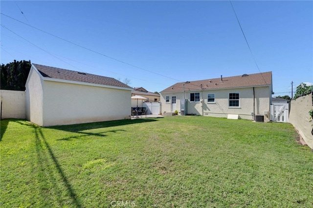 back of house with a yard, stucco siding, a fenced backyard, and central air condition unit