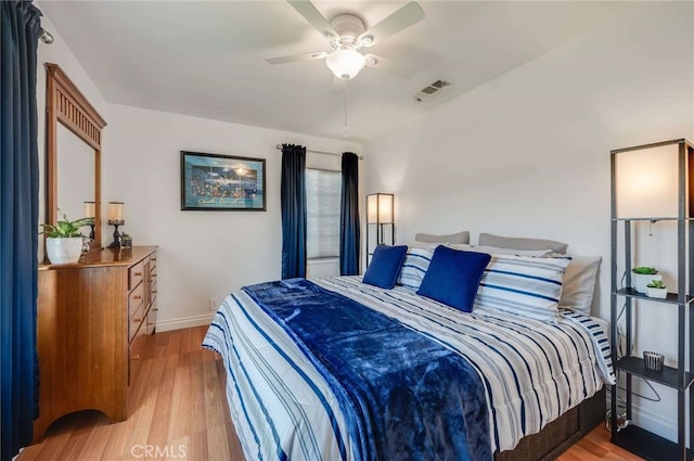 bedroom featuring light wood-style floors, baseboards, visible vents, and a ceiling fan