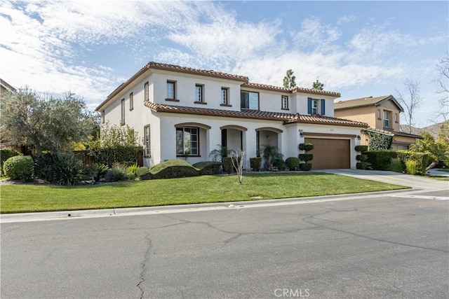 mediterranean / spanish house featuring driveway, stucco siding, a tile roof, and a front yard