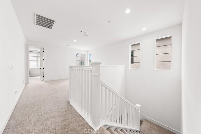 hallway with recessed lighting, light colored carpet, visible vents, an upstairs landing, and baseboards