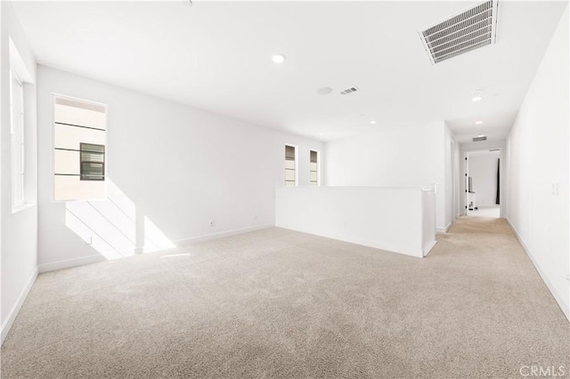 unfurnished room featuring light colored carpet, visible vents, baseboards, and recessed lighting