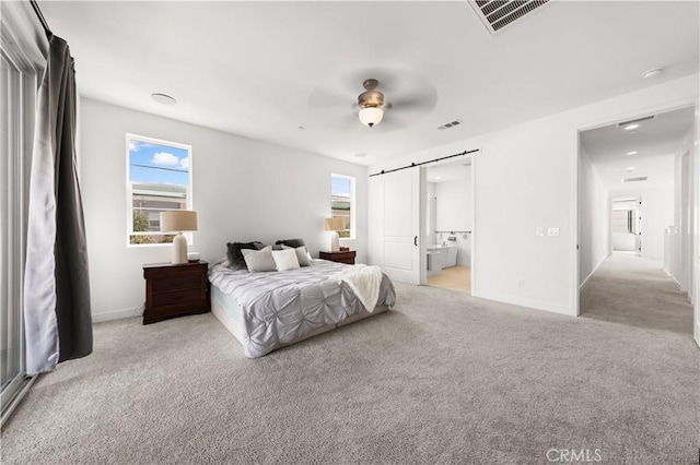 bedroom with a barn door, carpet flooring, visible vents, and baseboards