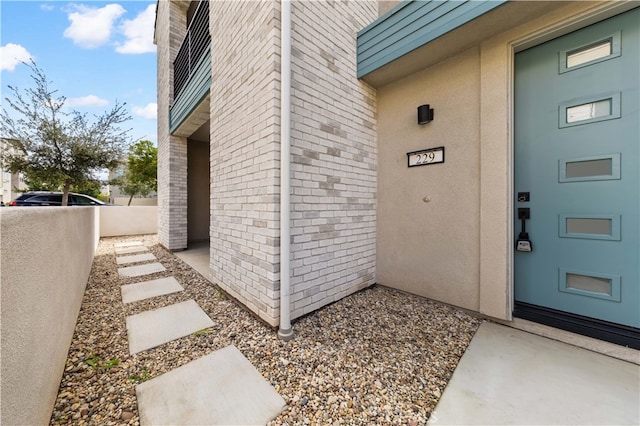 doorway to property featuring fence and stucco siding