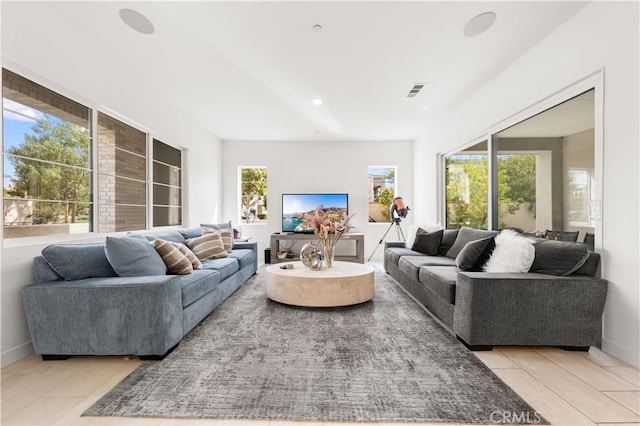 living room with light tile patterned floors, plenty of natural light, visible vents, and baseboards