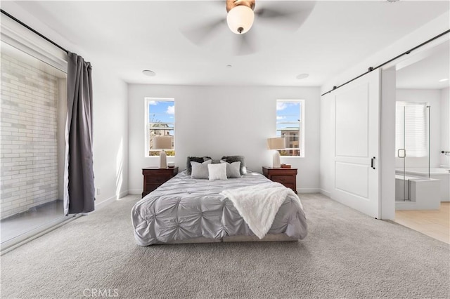 bedroom with light carpet, a barn door, and baseboards