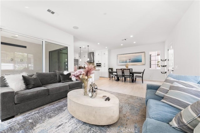 living area featuring recessed lighting, visible vents, and light wood finished floors