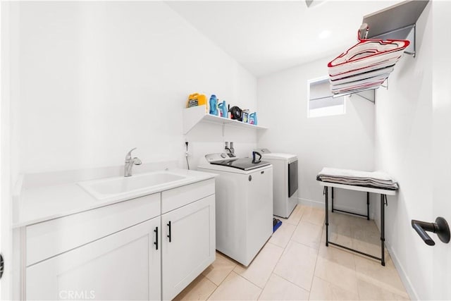 laundry room featuring cabinet space, baseboards, washing machine and dryer, a sink, and light tile patterned flooring