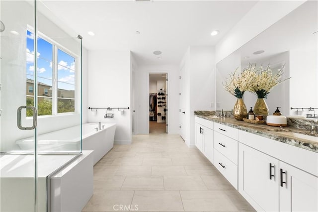 full bathroom with double vanity, a tub to relax in, a sink, and a shower stall