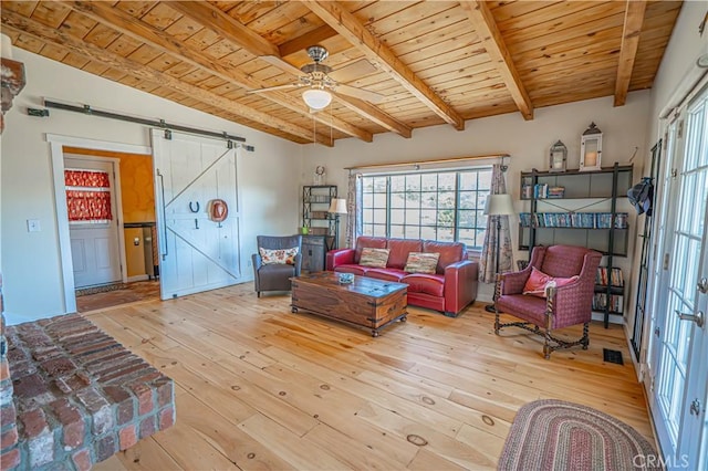 living room featuring lofted ceiling with beams, a barn door, wood ceiling, a ceiling fan, and wood-type flooring