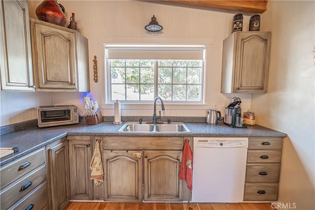 kitchen with a sink, dark countertops, a toaster, and dishwasher