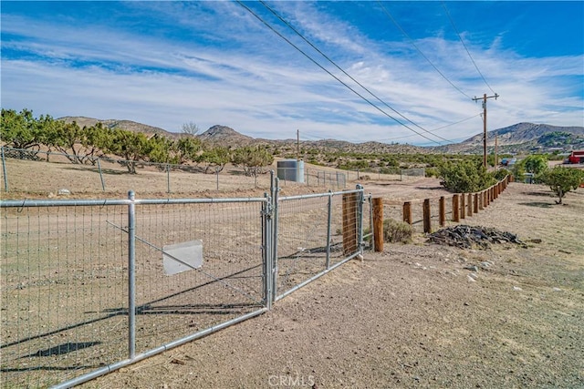 view of yard with a gate, a mountain view, fence, and a rural view