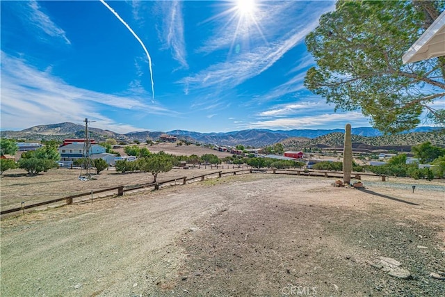 view of yard with a rural view, a mountain view, and fence