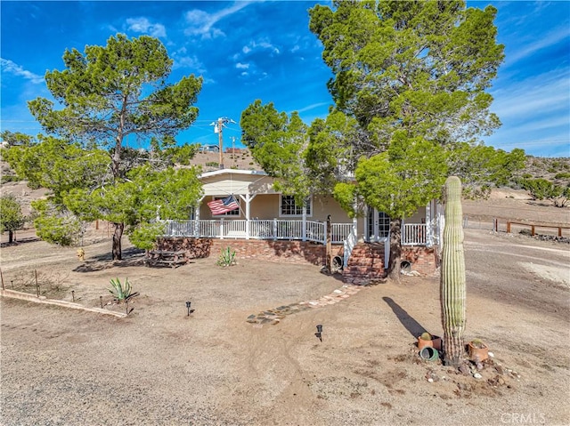 view of property hidden behind natural elements featuring a porch