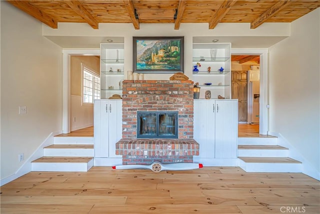 unfurnished living room with light wood-type flooring, wood ceiling, and a brick fireplace