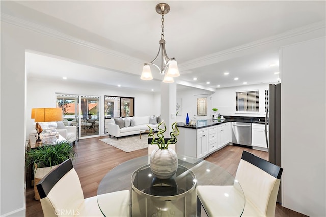 dining area featuring recessed lighting, an inviting chandelier, wood finished floors, and crown molding