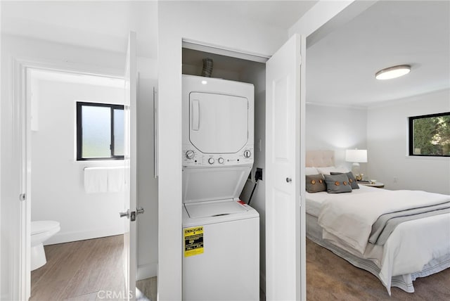 bedroom featuring stacked washer / drying machine and wood finished floors