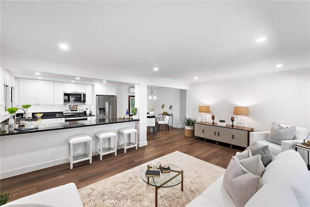 living area featuring baseboards, dark wood finished floors, and recessed lighting