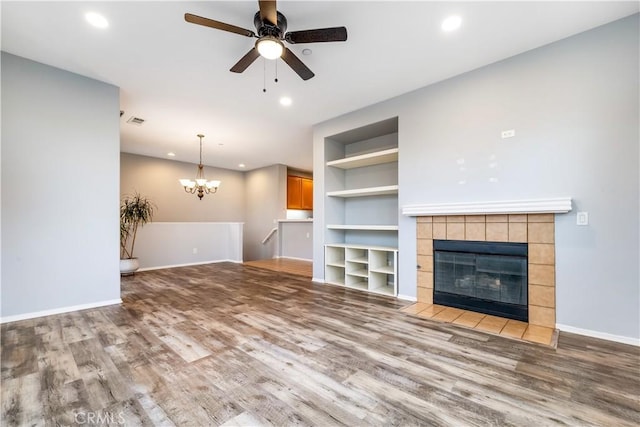 unfurnished living room featuring recessed lighting, a tiled fireplace, baseboards, and wood finished floors