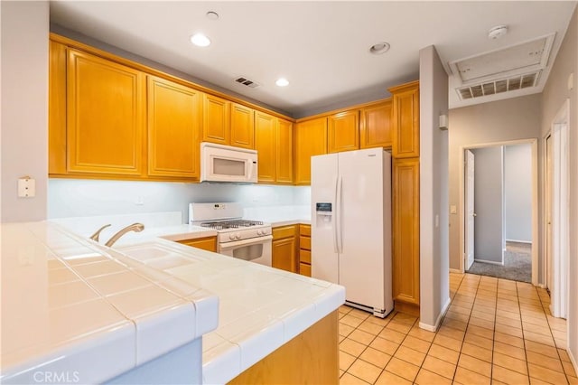 kitchen featuring tile countertops, white appliances, visible vents, and a sink