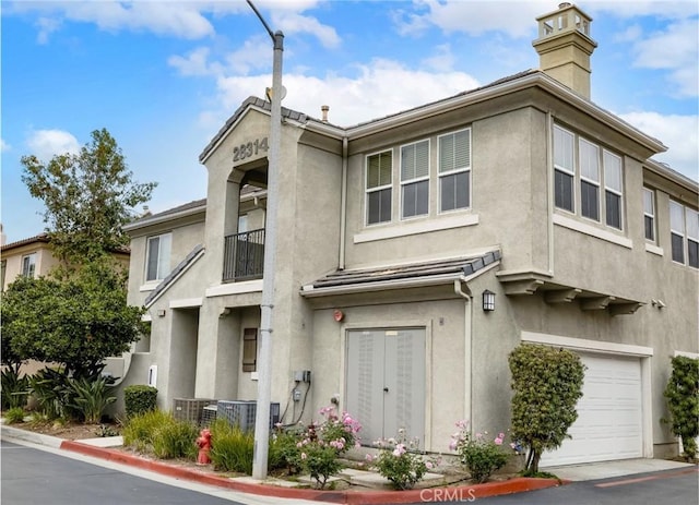 multi unit property featuring an attached garage, a chimney, and stucco siding