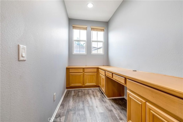 interior space featuring built in study area, baseboards, and wood finished floors