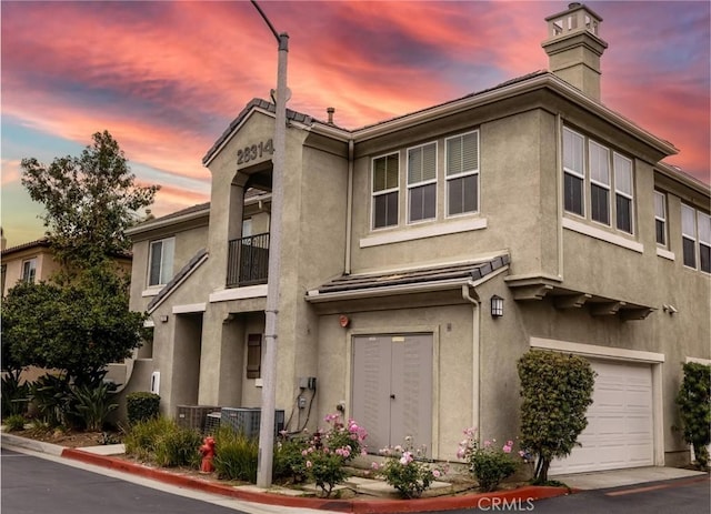 view of property featuring a garage, a chimney, and stucco siding