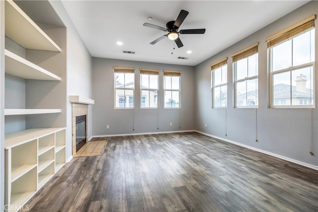 unfurnished living room with dark wood-style flooring, visible vents, plenty of natural light, and baseboards