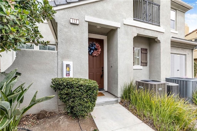 doorway to property featuring central AC unit and stucco siding