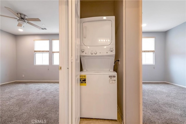 washroom featuring light carpet, stacked washer and dryer, baseboards, and laundry area