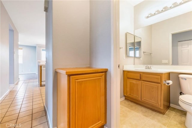 bathroom with toilet, tile patterned flooring, baseboards, and vanity