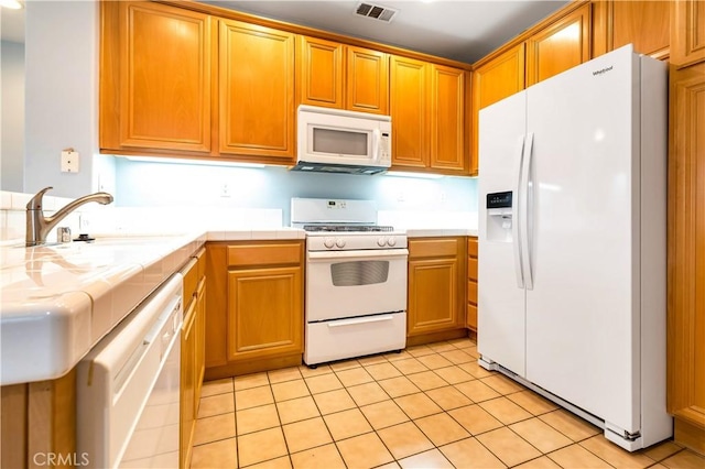 kitchen with white appliances, tile counters, visible vents, a sink, and light tile patterned flooring