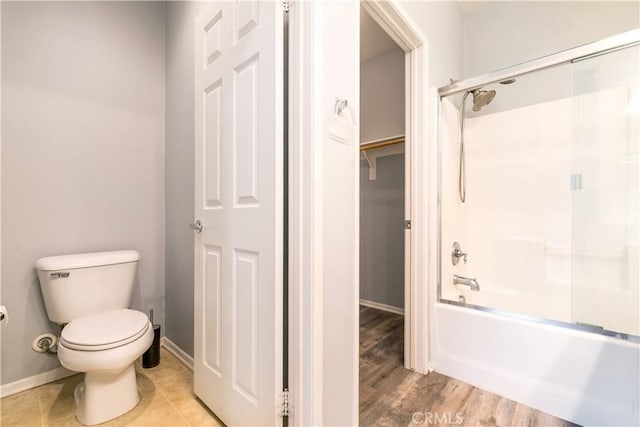 full bath featuring toilet, baseboards, shower / washtub combination, and wood finished floors