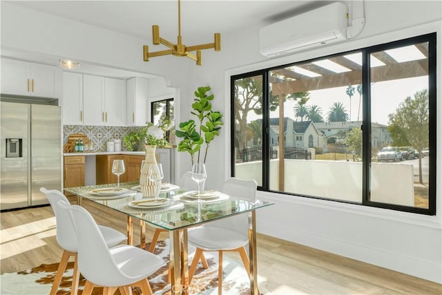 dining space with a wall unit AC and light wood-type flooring