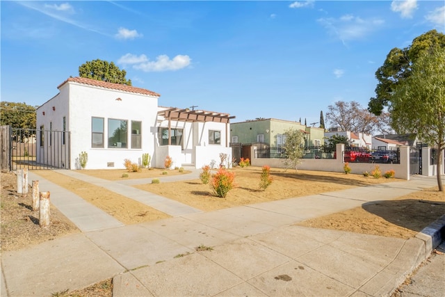 mediterranean / spanish home with a pergola, a gate, a fenced front yard, and stucco siding