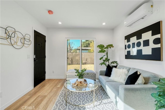 living area with baseboards, recessed lighting, a wall unit AC, and light wood-style floors