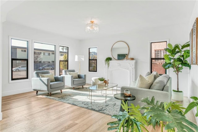 living area with baseboards, wood finished floors, and an inviting chandelier