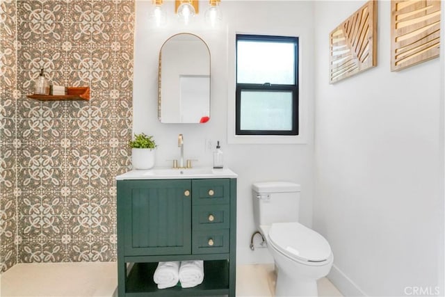 bathroom with toilet, tiled shower, and vanity