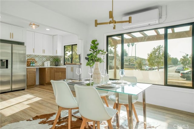 dining space with a wall mounted AC and light wood-style floors