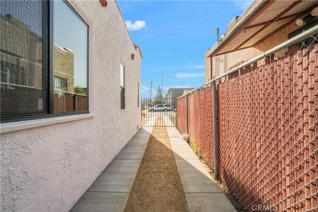 view of side of property with a gate, stucco siding, and fence