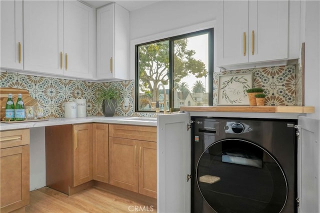 laundry room featuring a sink, cabinet space, washer / dryer, and light wood-type flooring
