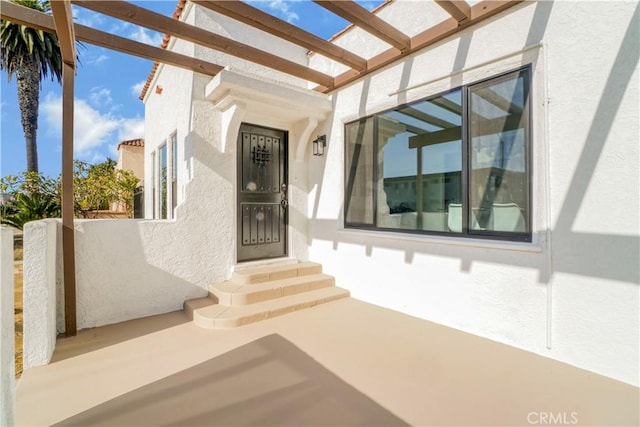 property entrance with a pergola and stucco siding