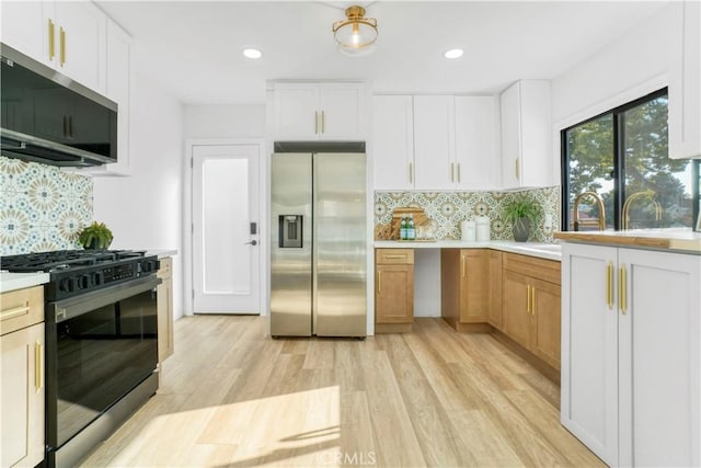 kitchen featuring light countertops, stainless steel appliances, tasteful backsplash, white cabinetry, and light wood-style floors