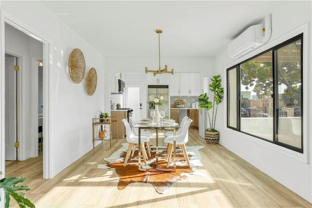 dining space featuring baseboards, a wall unit AC, light wood-style floors, and an inviting chandelier