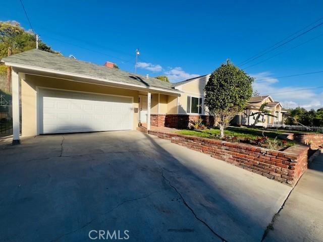 ranch-style house with driveway, an attached garage, and stucco siding