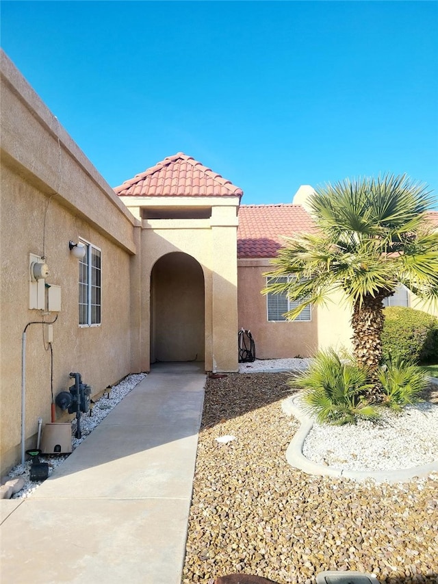 doorway to property with a tiled roof and stucco siding