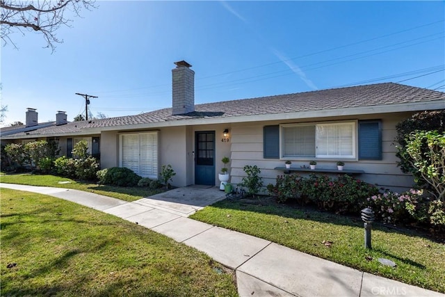 single story home featuring a chimney and a front yard