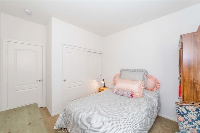 bedroom featuring baseboards, a closet, and light colored carpet