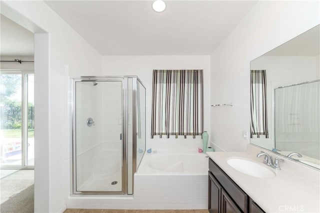 bathroom with a stall shower, a garden tub, and vanity